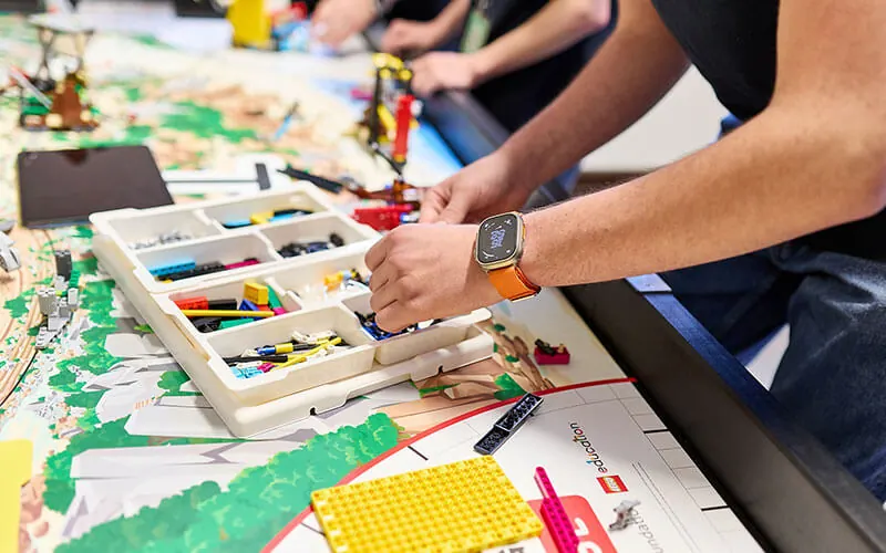 Hands placing LEGO elements on the competition model