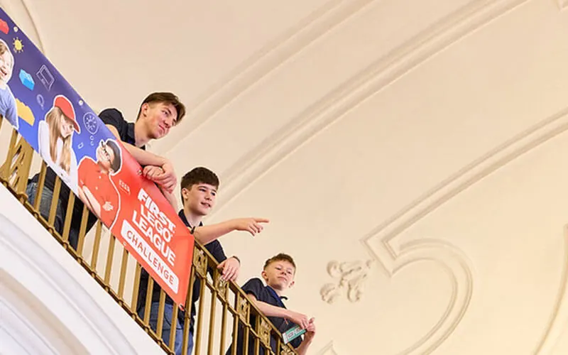 Teammitglieder blicken von der Empore mit Finalebanner in den Saal
