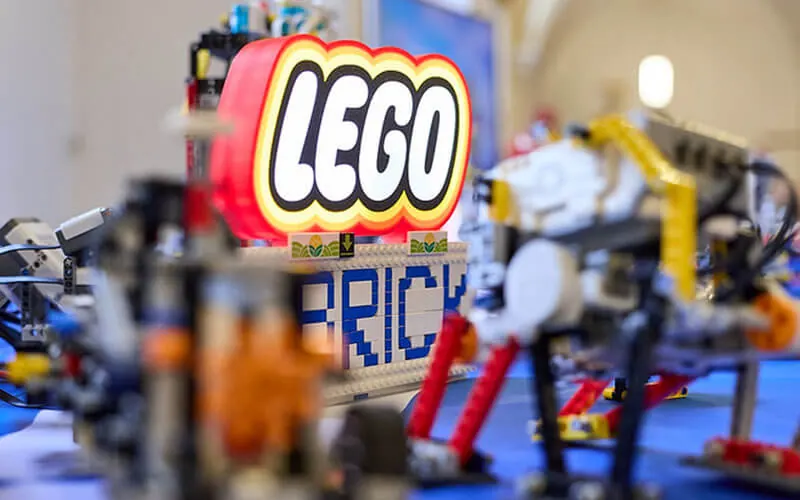 LEGO Robotermodell vor beleuchtetem LEGO Schild